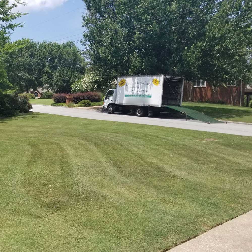 Company box truck parked at the curb beyond a large lawn mowed in wide curved stripes